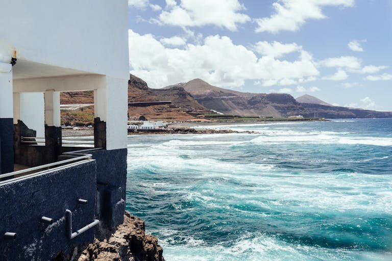 Breathtaking coastal view of Gran Canaria with waves hitting the shore under a sunny sky.