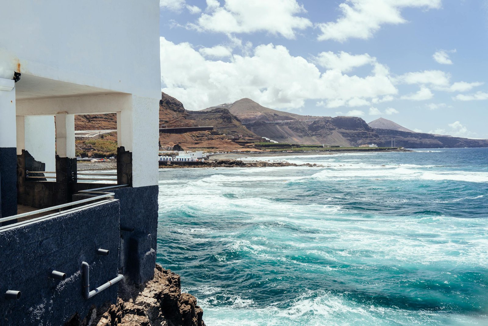 Breathtaking coastal view of Gran Canaria with waves hitting the shore under a sunny sky.