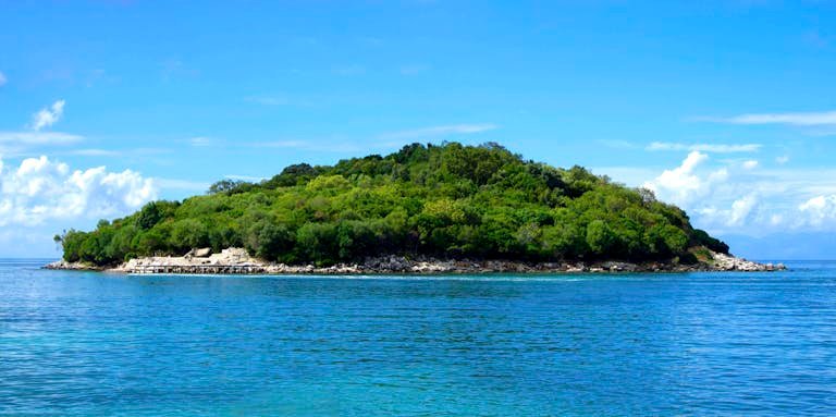 Scenic view of lush island surrounded by clear blue sea in Ksamil, Albania.